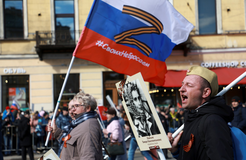  A participant carries a flag with the "Z" symbol in support of the Russian armed forces involved in a conflict in Ukraine, during the Immortal Regiment march on Victory Day, which marks the 77th anniversary of the victory over Nazi Germany in World War Two, in Saint Petersburg, Russia May 9, 2022. (photo credit: ANTON VAGANOV/ REUTERS)