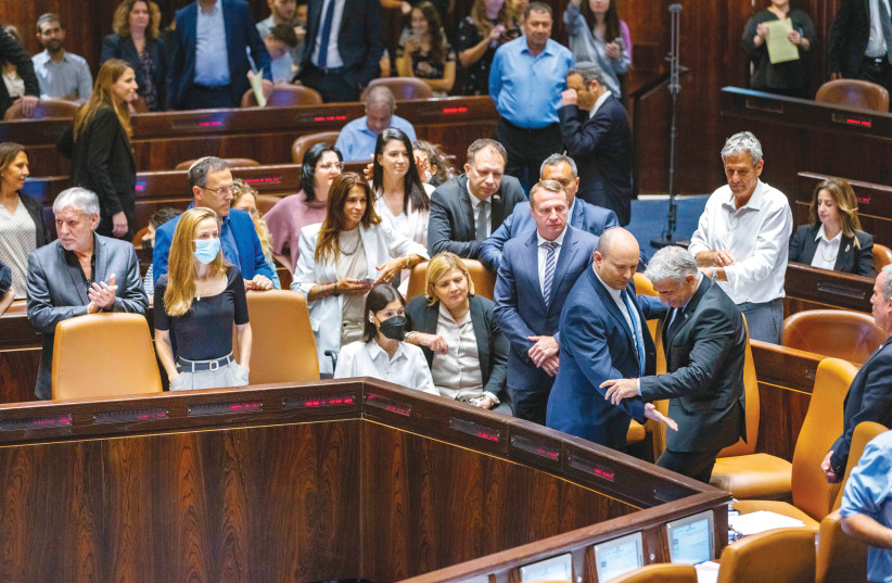  OUTGOING PRIME MINISTER Naftali Bennett directs his successor, Yair Lapid, to sit in the prime minister’s chair in the Knesset plenum, last Thursday.  (photo credit: OLIVIER FITOUSSI/FLASH90)