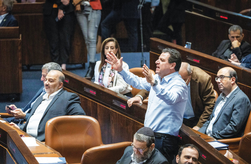  JOINT LIST leader MK Ayman Odeh stands and shouts his objections during a debate in the Knesset, as Ra’am leader MK Mansour Abbas sits to the left. (photo credit: YONATAN SINDEL/FLASH90)