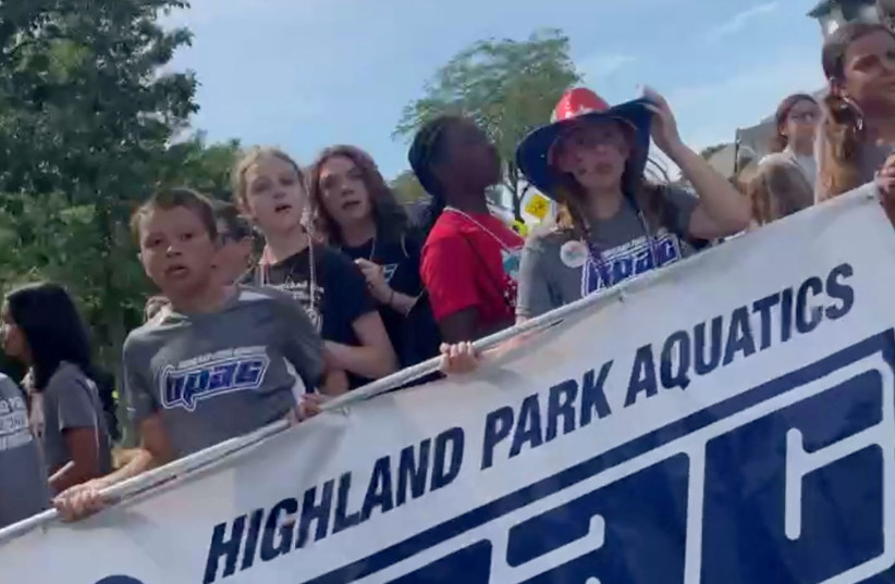  Children, carrying a Highland Park Aquatics banner, pause after hearing gunfire, at a Fourth of July parade in the Chicago suburb of Highland Park, Illinois, U.S. July 4, 2022 in this screengrab obtained from social media video (photo credit:  Gina Troiani-Solorio via REUTERS)