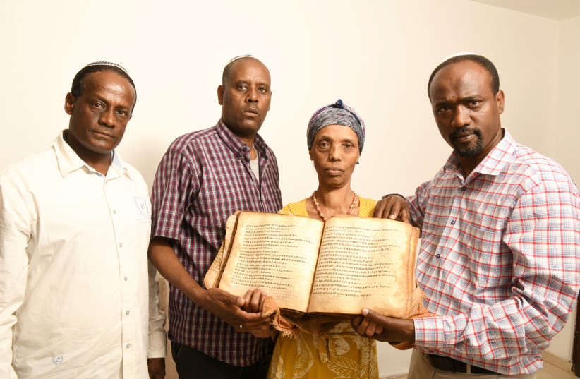  Ayanawo Ferada Senebato, right, and his family shown in Ashkelon, Israel, holding an ancient Orit book that they retrieved near Gondar, Ethiopia, in February 2022.  (photo credit: YOSSI ZELIGER)