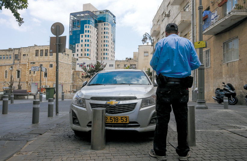  A POLICEMAN writes out a parking ticket to a car parked on a sidewalk in Jerusalem. (credit: NATI SHOHAT/FLASH90)