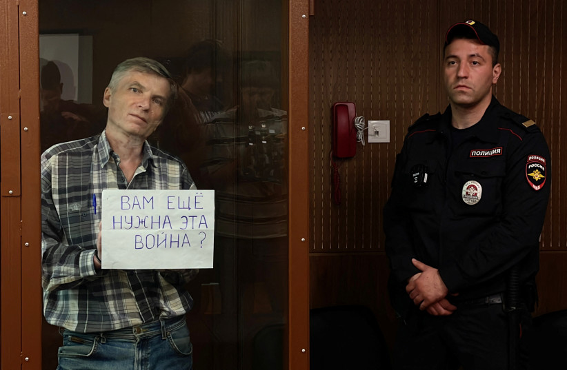  Moscow city councillor Alexei Gorinov holds a placard reading "Do you still need this war?" as he stands inside a defendants' cage during a court hearing in Moscow, Russia July 8, 2022 (photo credit: REUTERS/STRINGER)