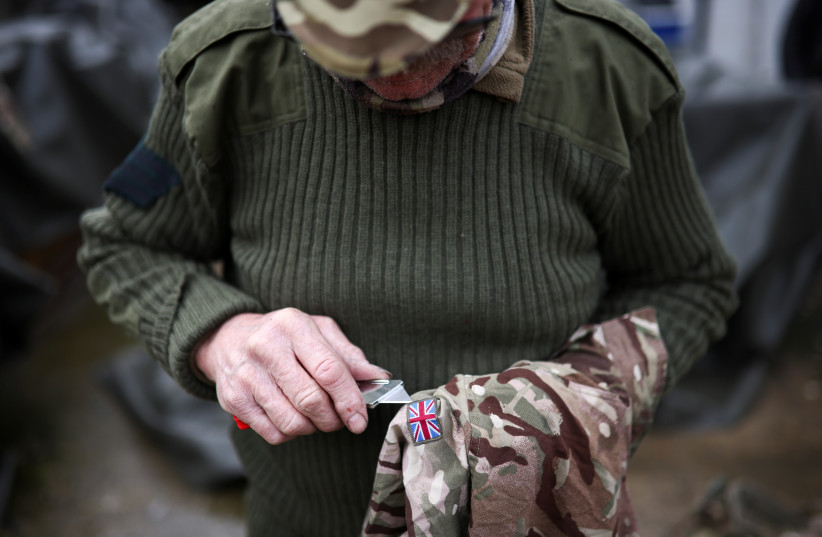  A former British Soldier known as Taft, de-badges military clothing at the military surplus store he runs in Folkestone, Britain, March 2, 2022 (photo credit: REUTERS/HENRY NICHOLLS)