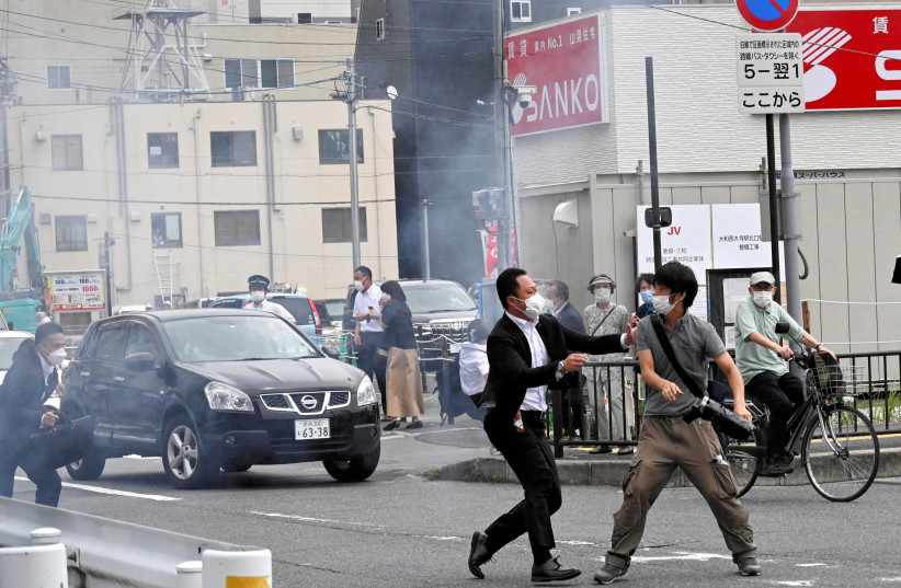  A police officer detains a man, believed to have shot former Japanese Prime Minister Shinzo Abe, in Nara, western Japan July 8, 2022  (photo credit: THE ASAHI SHIMBUN/REUTERS)