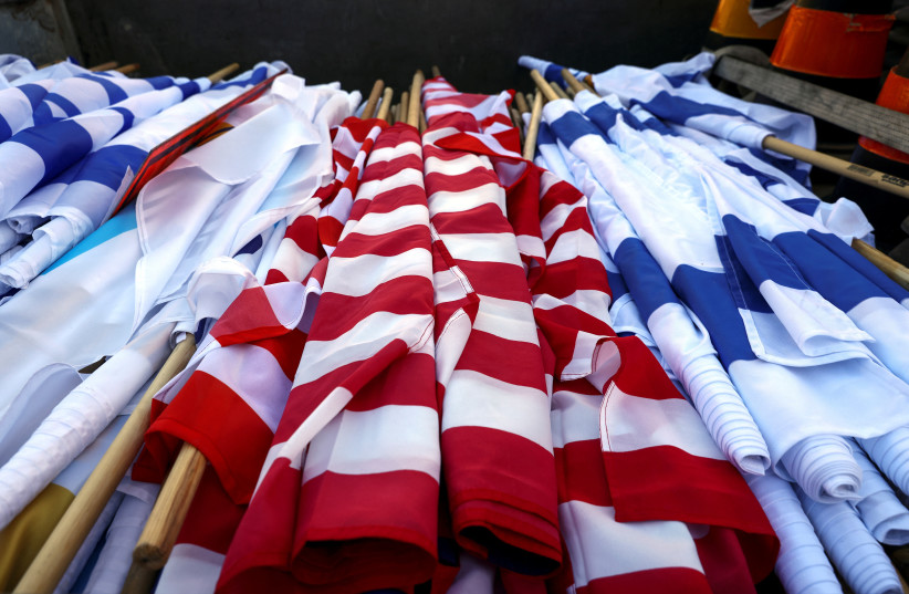 Israeli and US flags are rolled up before being set up, as part of preparations for US President Joe Biden's visit later this week, in Jerusalem, July 10, 2022. (photo credit:  REUTERS/Ronen Zvulun)
