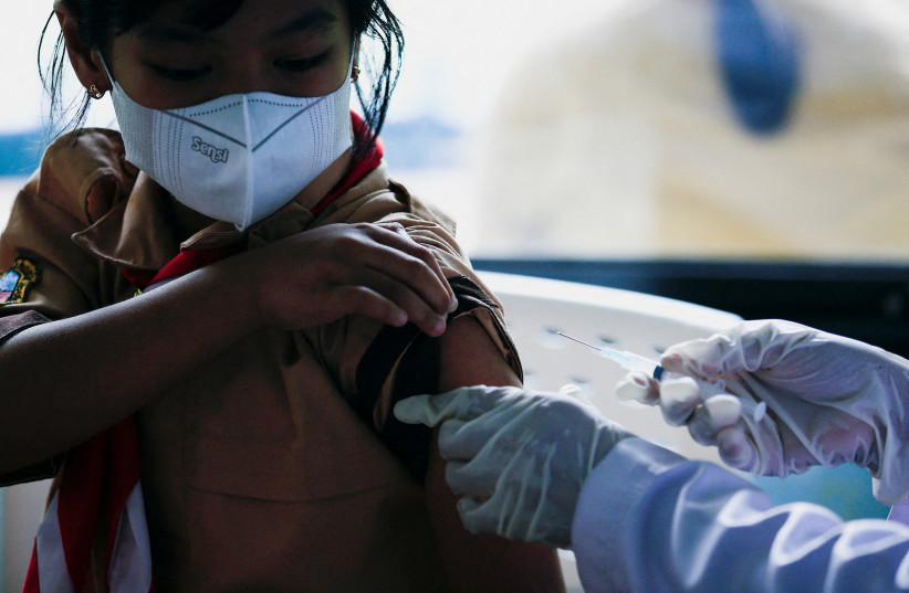  A child gets vaccinated against COVID-19 (photo credit: REUTERS/WILLY KURNIAWAN)