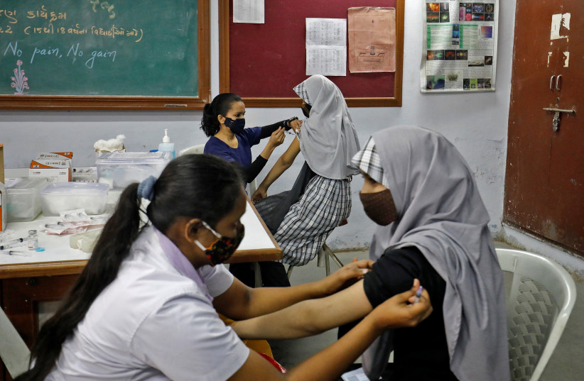  School girls receive a dose of Bharat Biotech's coronavirus disease (COVID-19) vaccine, Covaxin, during a vaccination drive for children aged 15-18 in Ahmedabad, India, January 4, 2022. (credit: REUTERS/AMIT DAVE)
