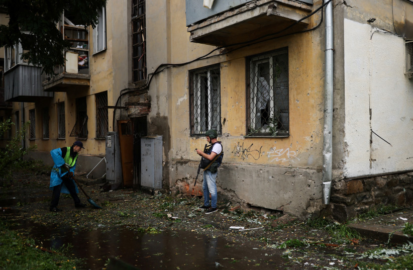 A man cleans an area of a residential building damaged by a Russian military strike, as Russia's invasion of Ukraine continues, in Kharkiv, Ukraine July 11, 2022. (photo credit: REUTERS/NACHO DOCE)