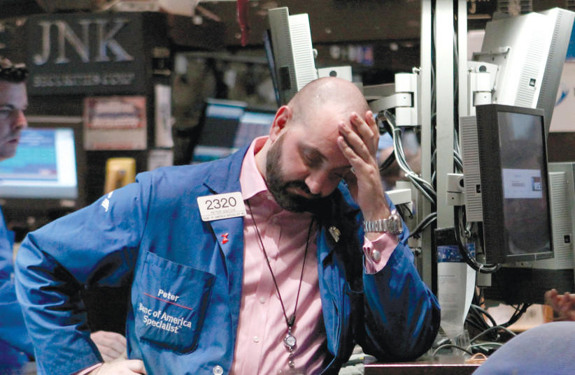  A trader works on the floor of the New York Stock Exchange, where stocks plunged to a bear-market low. (photo credit: BRENDAN MCDERMID/REUTERS)