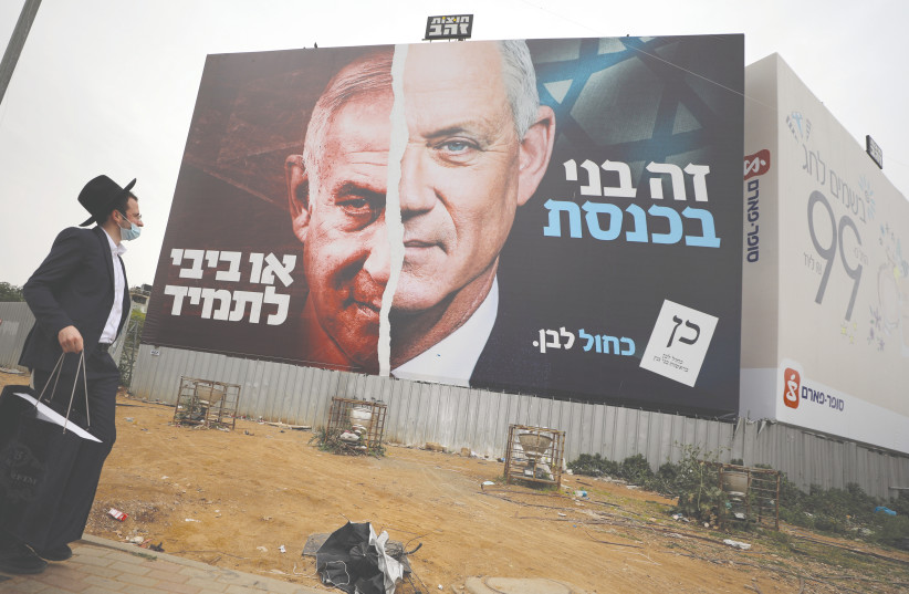  AN ULTRA-ORTHODOX man looks at a Blue and White party election campaign banner in Bnei Brak depicting Benny Gantz and Benjamin Netanyahu ahead of the March 2021 election. (photo credit: AMMAR AWAD/REUTERS)