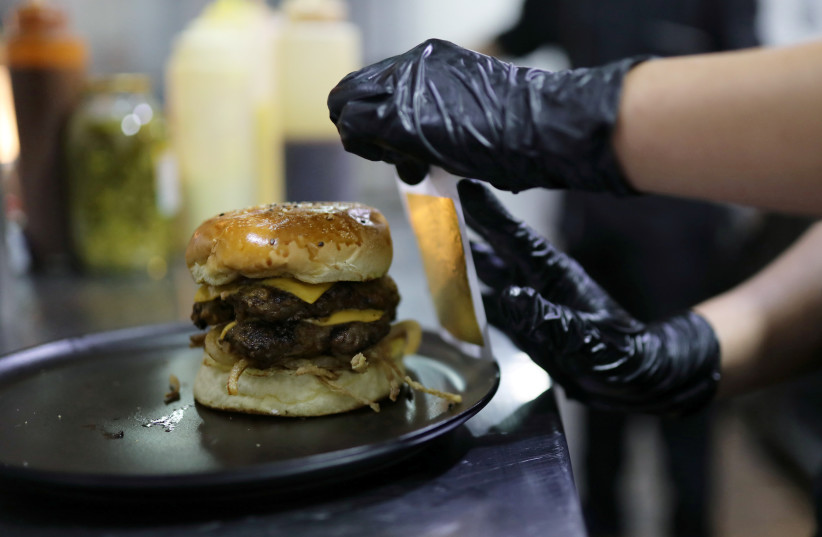  A cook covers a hamburger with gold foil at the Toro McCoy restaurant in Bogota, Colombia December 18, 2020. (credit: REUTERS/LUISA GONZALEZ)