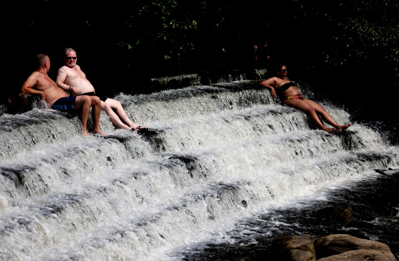 People relax in the River Derwent in the grounds of Chatsworth House during the heatwave, Derbyshire, Britain, July 19, 2022. (credit: REUTERS/CARL RECINE)