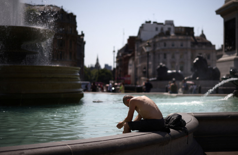 A man cools off in a water fountain during a heatwave, at Trafalgar Square in London, Britain, July 19, 2022. (photo credit: REUTERS/HENRY NICHOLLS)