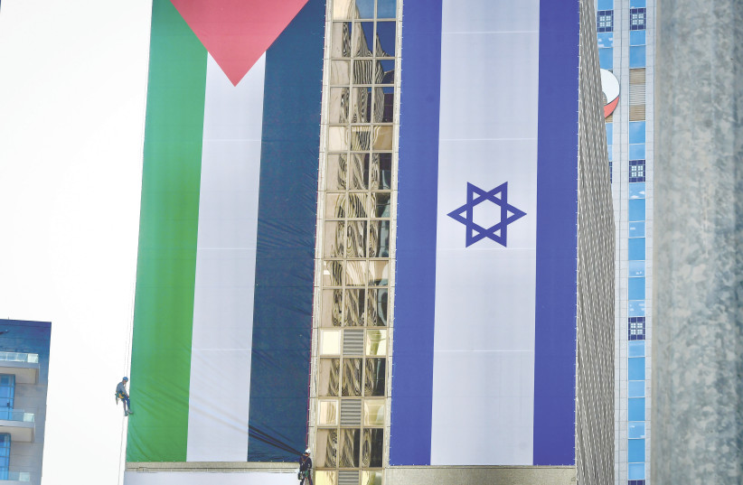  WORKERS HANG large Palestinian and Israeli flags in Ramat Gan, in June. (photo credit: AVSHALOM SASSONI/FLASH90)