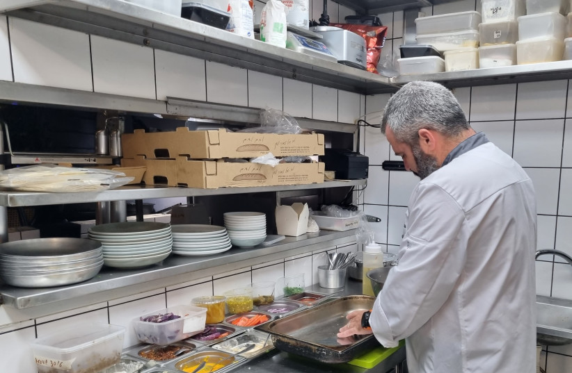 Chef Or Shapira prepares hybrid hamburgers at the Margoza Bar in Jaffa, Israel, Jul. 18, 2022. (credit: MAYA MARGIT/THE MEDIA LINE)