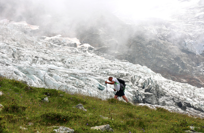  A hiker walks past the Bionnassay glacier, the smallest glacier of the Mont Blanc complex in France, which is shrinking under the the influence of global warming, according to many scientists, August 18, 2021.  (credit: REUTERS/YANN TESSIER)