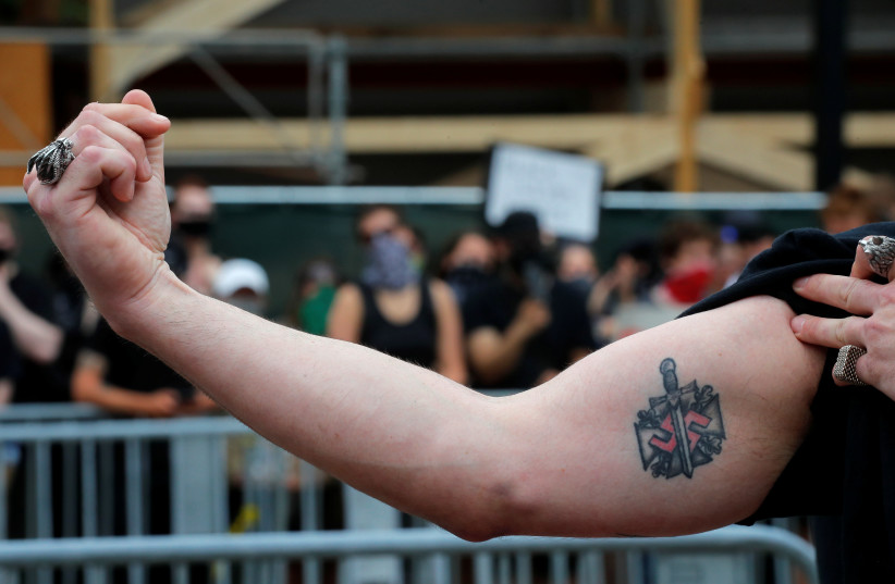  A man wearing a “Nationalist Social Club 131” (NSC 131) shirt shows his swastika tattoo during a pro-police rally, following weeks of protests against racial inequality in the aftermath of the death in Minneapolis police custody of George Floyd, in Boston, Massachusetts, US. June 27, 2020. (credit: BRIAN SNYDER/REUTERS)