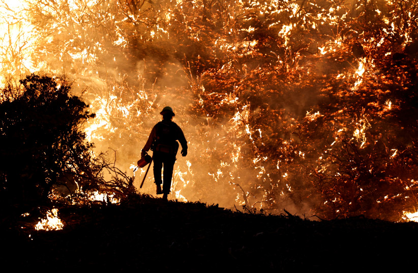 A firefighter works as the Caldor Fire burns in Grizzly Flats, California, US, August 22, 2021. (photo credit: REUTERS/FRED GREAVES/FILE PHOTO)