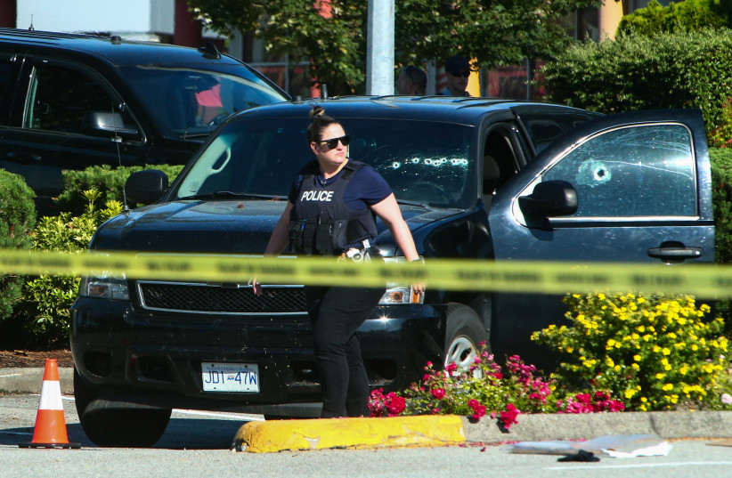 Police officers stand near a crime scene after authorities alerted residents of multiple shootings targeting transient victims in the Vancouver suburb of Langley, British Columbia, Canada, July 25, 2022. (photo credit: REUTERS/Jesse Winter)