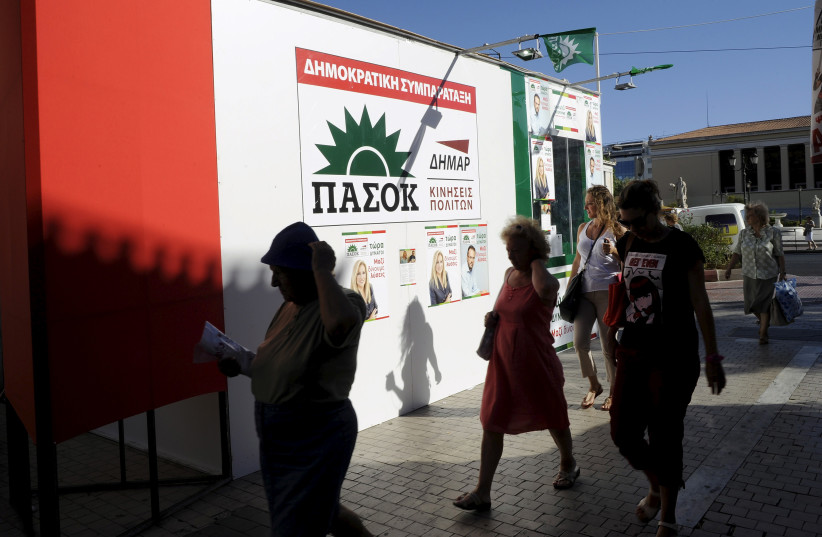 People walk in front of a pre-election kiosk of the Greek Socialist party PASOK in Athens, Greece, September 17, 2015. (credit: REUTERS/MICHALIS KARAGIANNIS)
