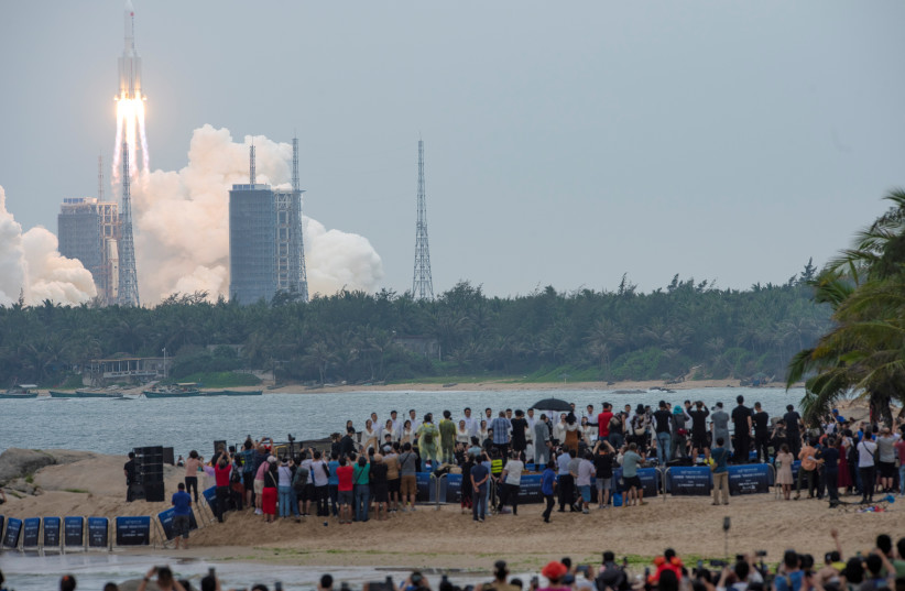  People watch from a beach as the Long March-5B Y2 rocket, carrying the core module of China's space station Tianhe, takes off from Wenchang Space Launch Center in Hainan province, China April 29, 2021. (credit: CHINA DAILY VIA REUTERS)
