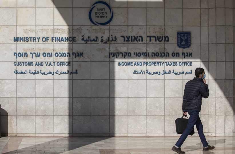  A man wearing a face mask walks outside the Tax Authorities offices in Jerusalem on November 23, 2020.  (credit: OLIVIER FITOUSSI/FLASH90)