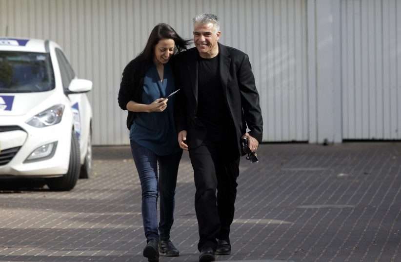 Yesh Atid leader Yair Lapid (R) and wife Lihi walk to a polling station before voting in Tel Aviv, March 17, 2015. (credit: REUTERS/STRINGER)