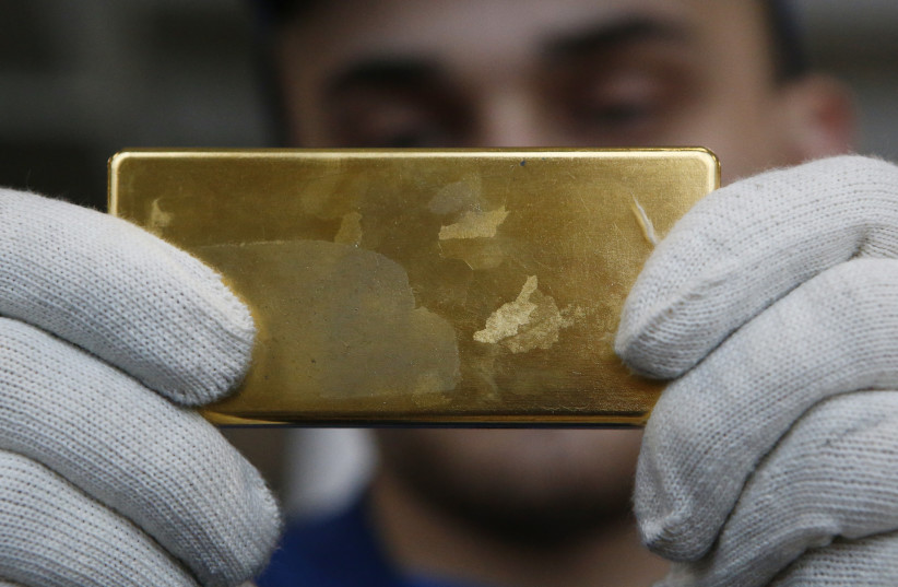  An employee shows gold bar at the Prioksky Non-Ferrous Metals Plant in Kasimov, Russia February 14, 2017. Picture taken February 14, 2017.  (photo credit: REUTERS/SERGEI KARPUKHIN)
