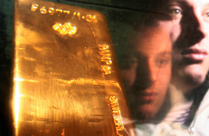  A tourist is seen reflected in perspex as he views a bar of gold bullion in the museum of the Bank of England in London. Photograph taken on March 25, 2008. (credit: REUTERS/LUKE MACGREGOR)