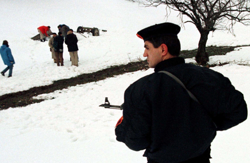  A Kosovo Liberation Army soldier stands guard January 5 as international monitors (rear) examine the site of an alleged mass grave near Topil village in the Caraleva mountains. (credit: RS/KM/REUTERS)