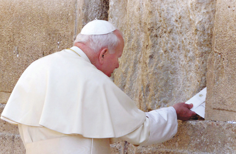  POPE JOHN Paul II places a written prayer into a crevice in the stones of the Western Wall, in 2000 (photo credit: REUTERS)
