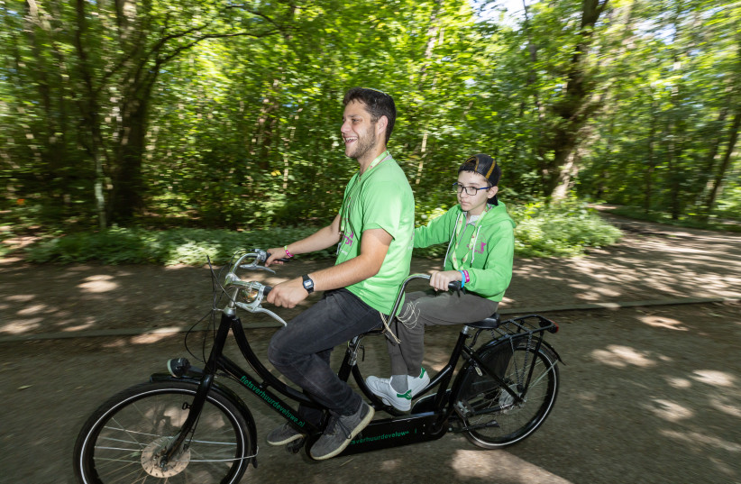  COUNSELOR YITZHAK ‘Schnitzel’ Jacobson, who made sure the spirits of the youngest campers were kept high, bikes with a camper. When in Holland... you ride a bicycle. (credit: Baruch Greenberg/Zichron Menachem)