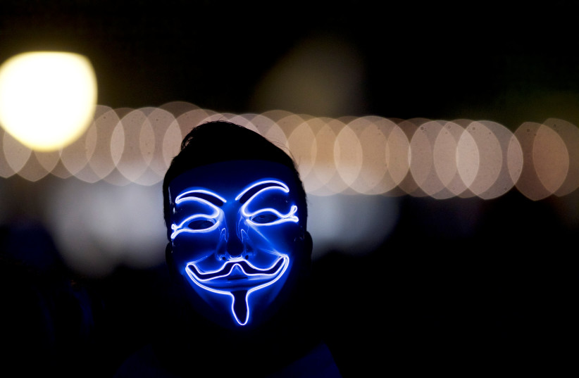  A man wears an "anonymous" mask (photo credit: REUTERS)