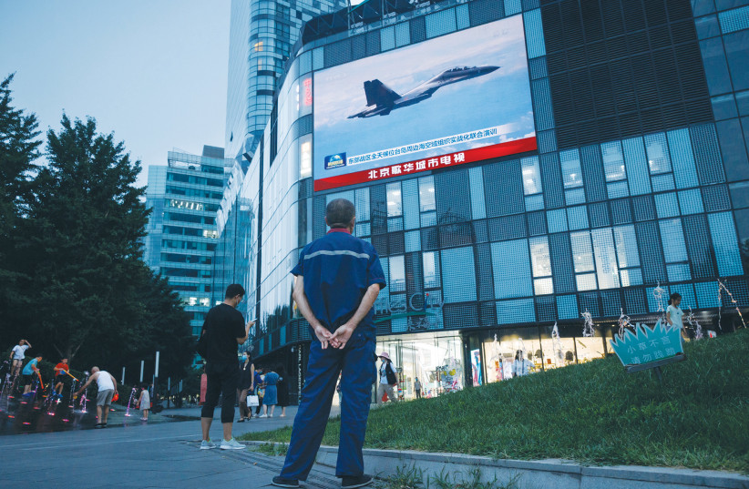 A MAN at a shopping center in Beijing on August 3 watches a CCTV news broadcast showing a fighter jet during military operations near Taiwan by the Chinese People’s Liberation Army. (photo credit: THOMAS PETER/REUTERS)