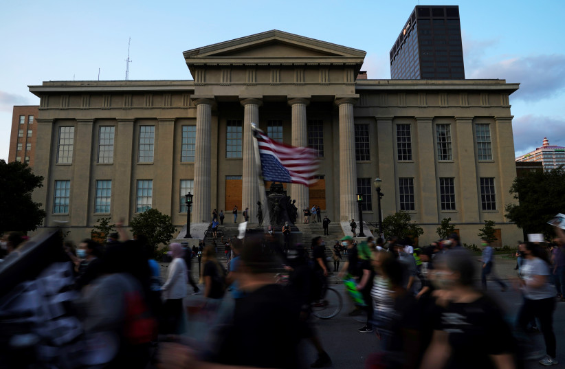  Demonstrators march past the Louisville Metro Hall during a protest after a grand jury decided not to bring homicide charges against police officers involved in the fatal shooting of Breonna Taylor, in Louisville, Kentucky September 26, 2020.  (credit: REUTERS/BRYAN WOOLSTON)
