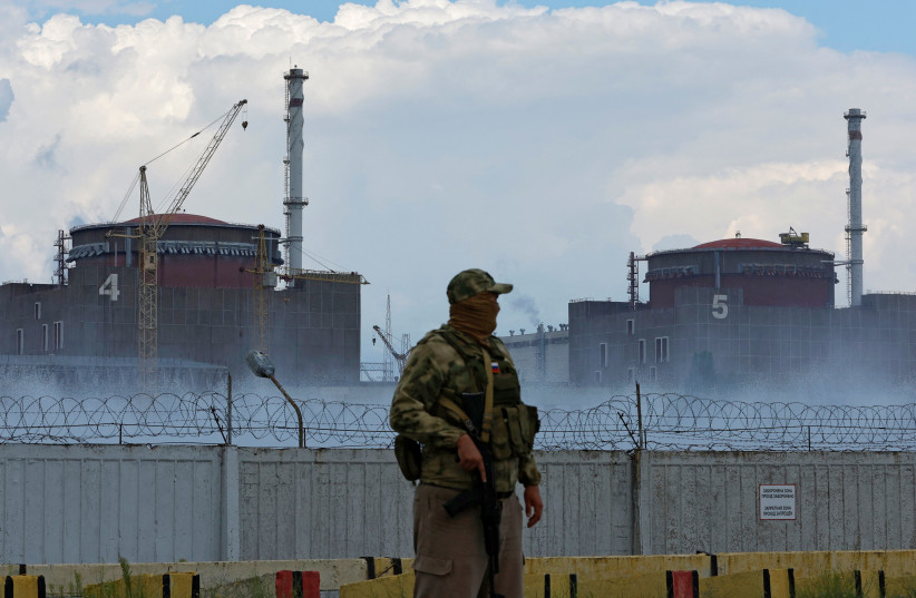 A serviceman with a Russian flag on his uniform stands guard near the Zaporizhzhia Nuclear Power Plant in the course of Ukraine-Russia conflict outside the Russian-controlled city of Enerhodar in the Zaporizhzhia region, Ukraine, August 4, 2022. (photo credit: REUTERS/ALEXANDER ERMOCHENKO)