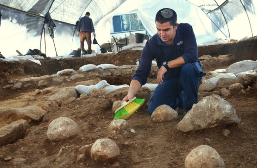  Kfir Arbiv, Israel Antiquities Authority excavation director, cleans a ballista stone at the Russian Compound excavation site. (credit: YOLI SCHWARTZ/ISRAEL ANTIQUITIES AUTHORITY)
