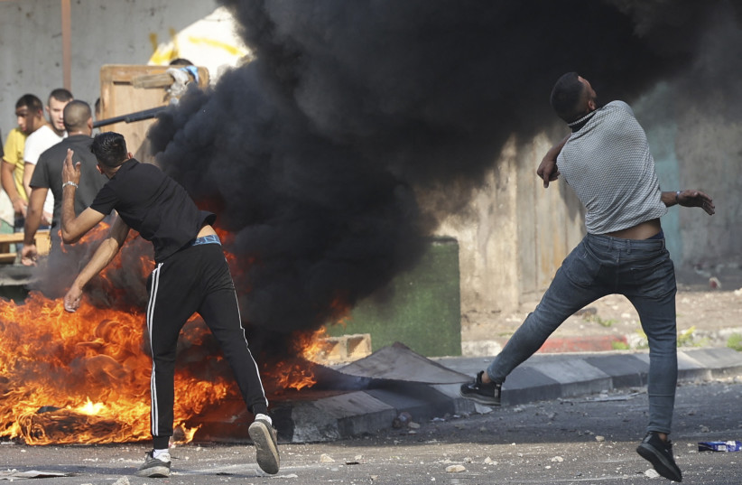  Palestinian protesters hurl stones during clashes with Israeli security forces after a raid in the old town of Nablus, in the occupied West Bank, on August 9, 2022 (credit: JAAFAR ASHTIYEH/AFP via Getty Images)