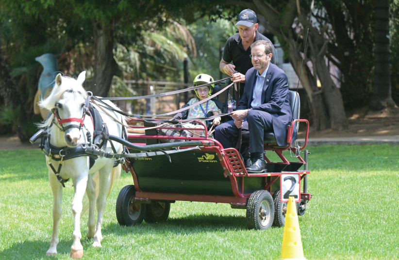  President Isaac Herzog, join in pony petting therapy with a five-year-old child at Beit Loewenstein rehabilitation hospital. (credit: KOBI GIDEON/GPO)