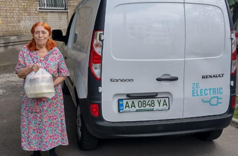  A woman takes out an aid package from an electric car owned by the Jewish Federations of Ukraine in Kyiv, Ukraine, Aug. 1, 2022.  (photo credit: Jewish Federation of Ukraine)