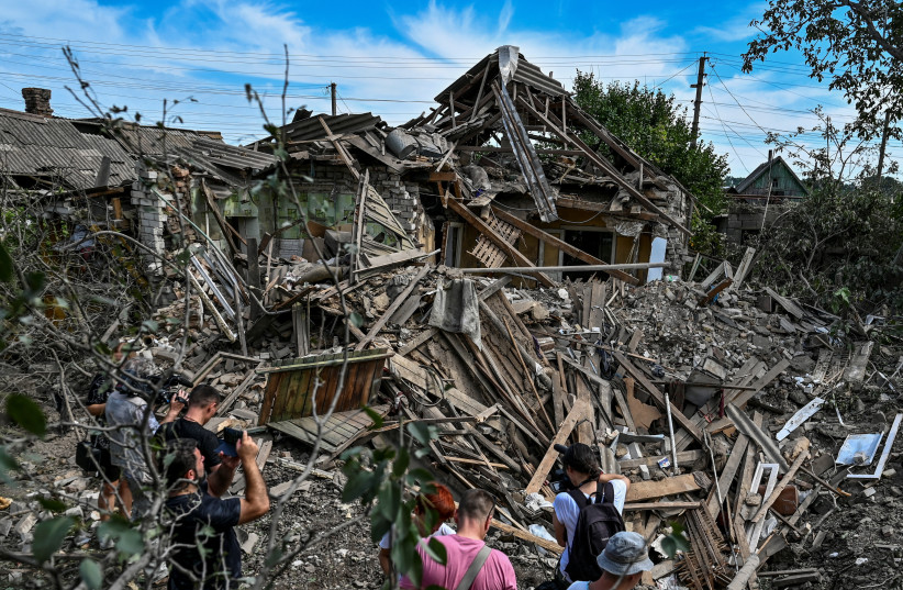 People stand next to a residential house destroyed by a Russian missile strike in the settlement of Kushuhum, as Russia's attack on Ukraine continues, in Zaporizhzhia region, Ukraine August 10, 2022. (photo credit: REUTERS/Dmytro Smolienko)