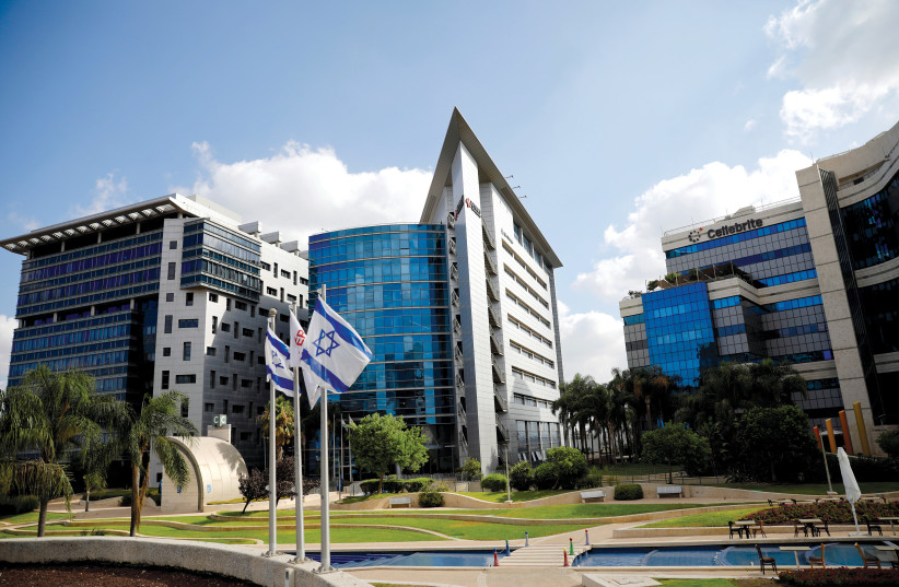 Des drapeaux israéliens flottent dans un parc d'activités abritant des entreprises de haute technologie, à Ofer Park à Petah Tikva. (crédit : RONEN ZVULUN/REUTERS)