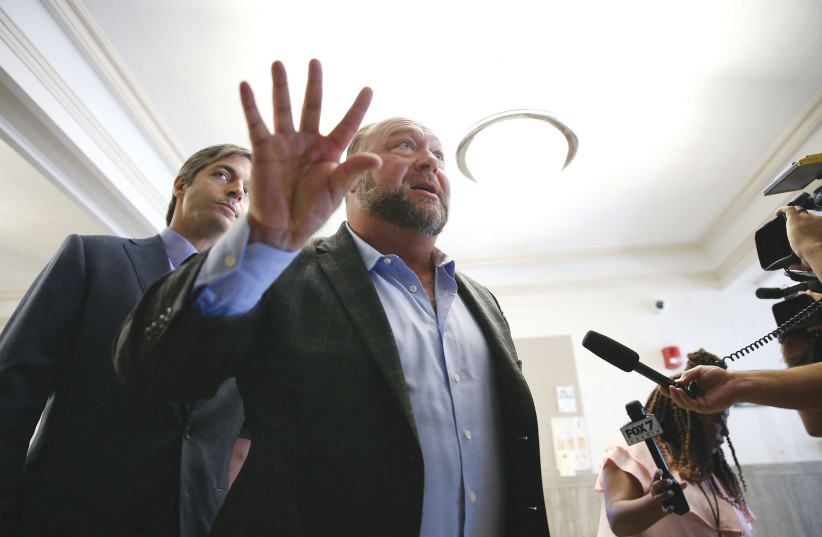  ALEX JONES talks to media outside the Travis County Courthouse in Austin, Texas, which this week ruled he must pay bereaved parents compensation for falsely claiming the Sandy Hook school massacre was a hoax (photo credit:  BRIANA SANCHEZ/POOL VIA REUTERS)