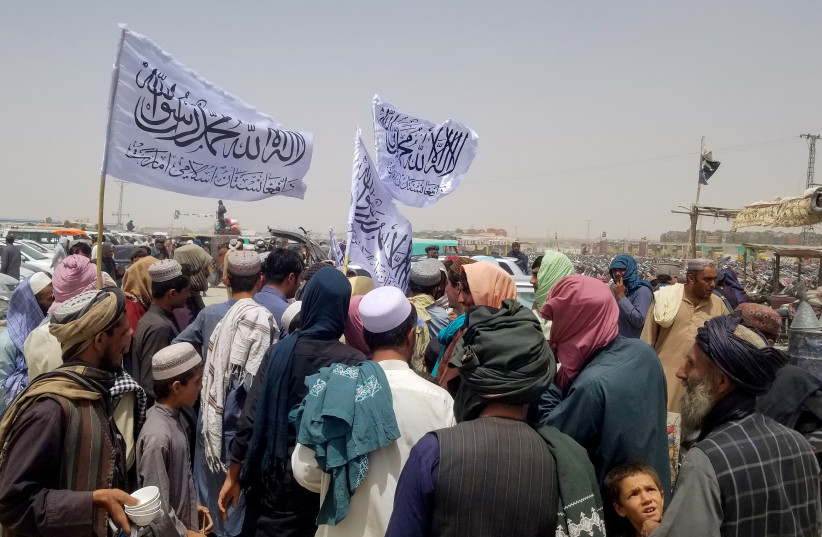  People with Taliban's flags gather to welcome a man (not pictured) who was released from prison in Afghanistan, upon his arrival at the Friendship Gate crossing point at the Pakistan-Afghanistan border town of Chaman, Pakistan August 16, 2021.  (credit: REUTERS/SAEED ALI ACHAKZAI)