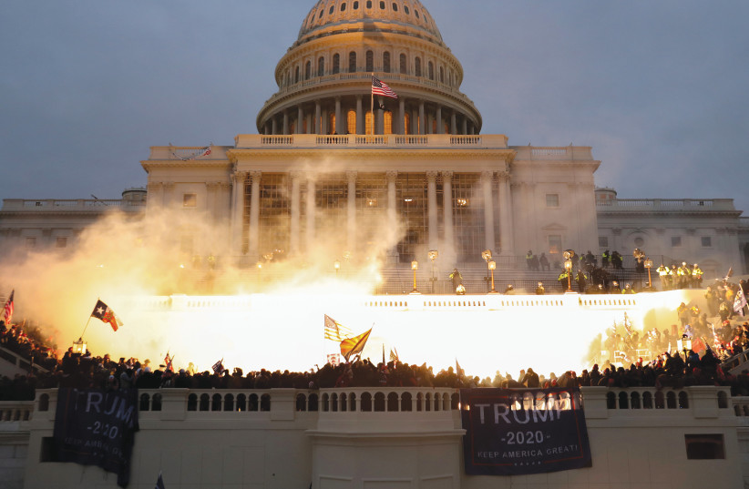 AN EXPLOSION caused by a police munition is seen as supporters of then-US president Donald Trump riot in front of the Capitol Building, January 6, 2021. (credit: LEAH MILLIS/REUTERS)