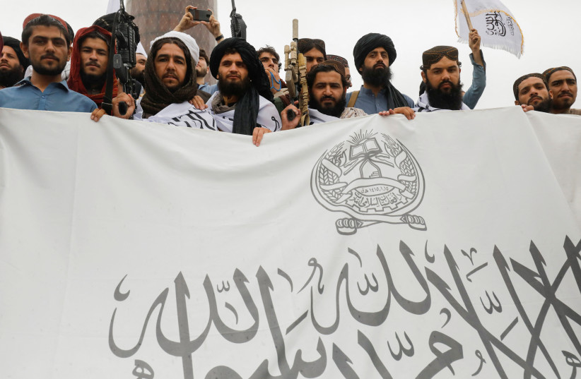  Taliban fighters hold an Islamic Emirate of Afghanistan flag on the first anniversary of the fall of Kabul on a street in Kabul, Afghanistan, August 15, 2022. (credit:  REUTERS/ALI KHARA)