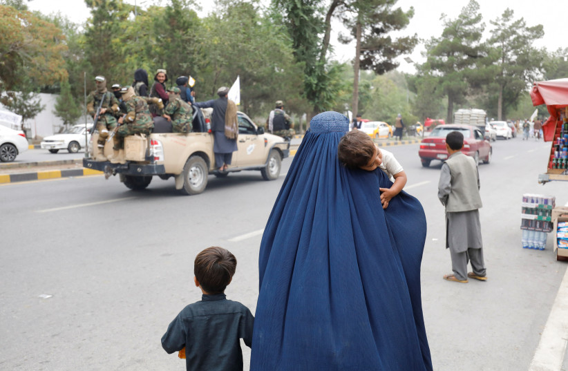  An Afghan woman walks with her children on the anniversary of the fall of Kabul on a street in Kabul, Afghanistan, August 15, 2022. (credit:  REUTERS/ALI KHARA)