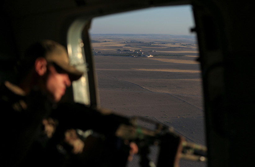 Un soldat russe regarde par un hélicoptère lors d'une patrouille au-dessus de Kobani, en Syrie, le 19 juillet 2022. (Crédit : REUTERS/Orhan Qereman)