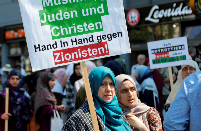 A protester holds a placard reading "Muslims, Jews and Christians, hand in hand against Zionists" during a demonstration marking al-Quds Day (Jerusalem Day), in Berlin, Germany June 1, 2019 (photo credit: REUTERS/FABRIZIO BENSCH)